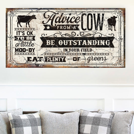 May include: A rustic white sign with black text and a distressed look. The sign reads &#39;Advice from a Cow: It&#39;s OK to be a little moo-dy. Be outstanding in your field. Eat plenty of greens.&#39; The sign features a black silhouette of a cow in the top left corner and a black silhouette of a calf in the top right corner.