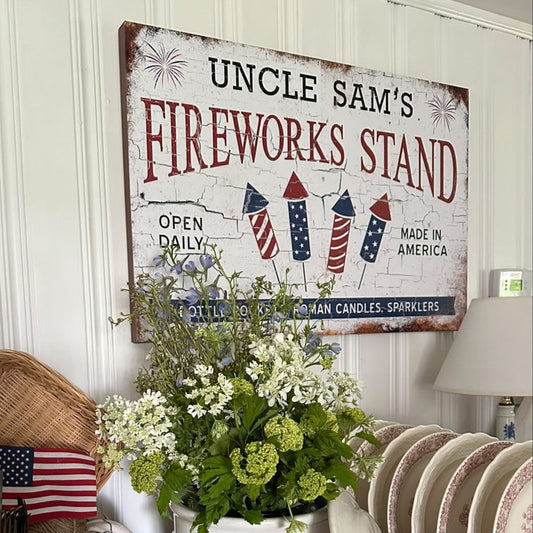 Decorative sign for 'Uncle Sam's Fireworks Stand' with patriotic elements on a wall.
